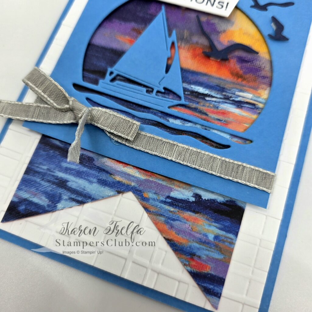 scenic-coast-sailboat-die-cut-detail Close-up of Azure Afternoon sailboat die cut and gray granite ribbon bow on a Scenic Coast Stampin' Up card with embossed white layer and painted coastal designer paper pennant at the bottom